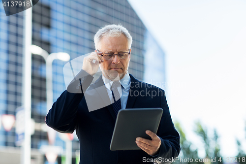 Image of senior businessman with tablet pc on city street