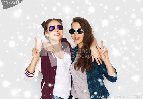 Image of smiling teenage girls in sunglasses showing peace