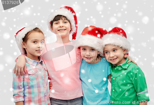 Image of happy little children in santa hats hugging