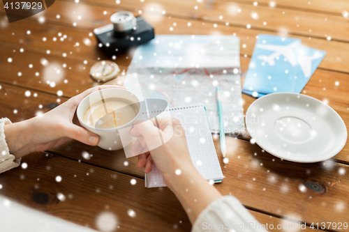 Image of close up of hands with coffee cup and travel stuff