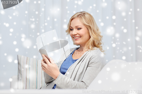 Image of smiling woman with smartphone texting at home