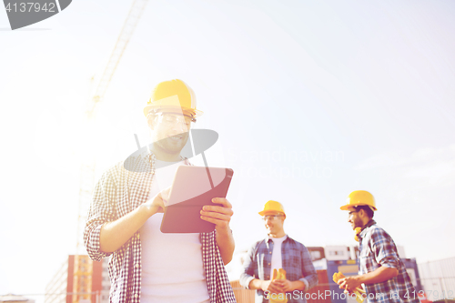 Image of smiling builders in hardhats with tablet pc