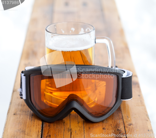 Image of Ski goggles and glass mug with fresh cold beer