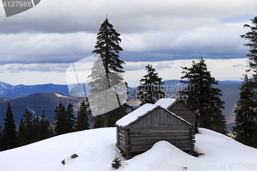 Image of Old wooden hut in winter snow mountains at gray day