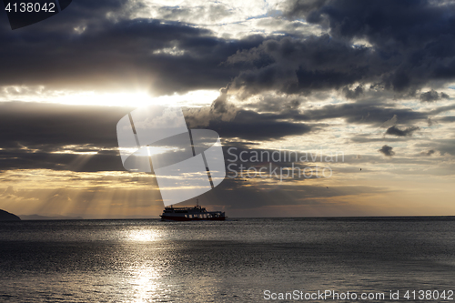 Image of Sea with sea boat and gray sky with sun at sunset