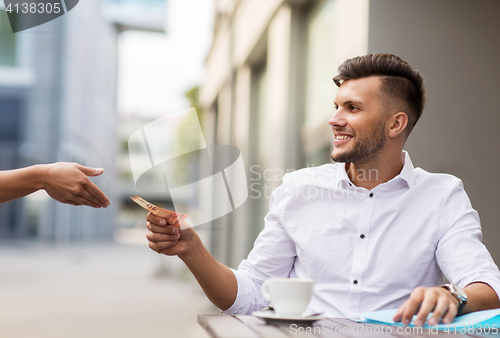 Image of man with euro money paying for coffee at cafe