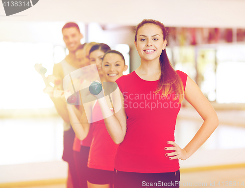 Image of group of smiling people with dumbbells in the gym