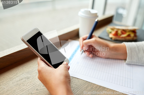 Image of woman with smartphone and paper form at cafe