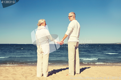 Image of happy senior couple holding hands summer beach