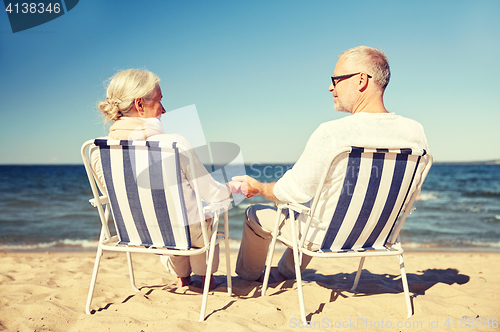 Image of happy senior couple in chairs on summer beach