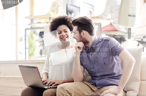 Image of happy creative team with laptop in office