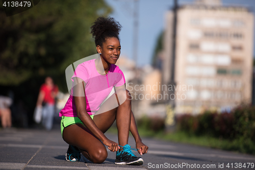 Image of African american woman runner tightening shoe lace