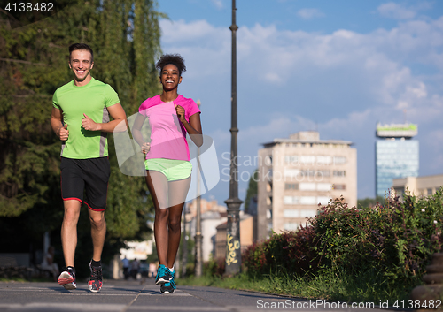 Image of young smiling multiethnic couple jogging in the city