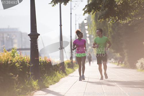 Image of young multiethnic couple jogging in the city
