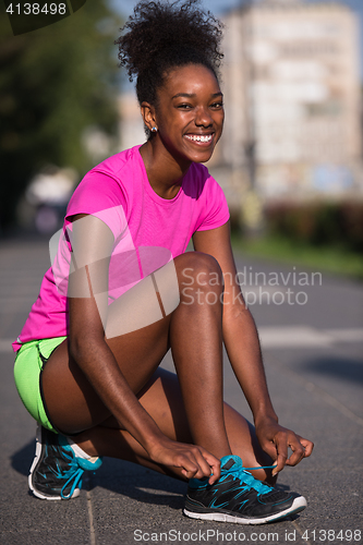 Image of African american woman runner tightening shoe lace