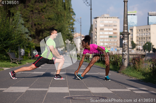 Image of jogging couple warming up and stretching in the city