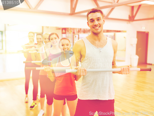 Image of group of smiling people working out with barbells