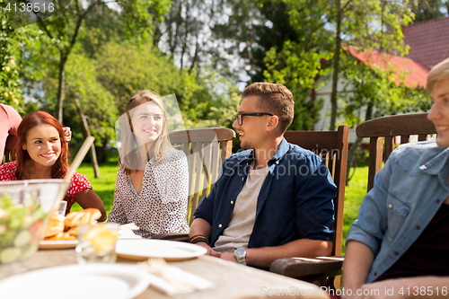 Image of happy friends having dinner at summer garden party