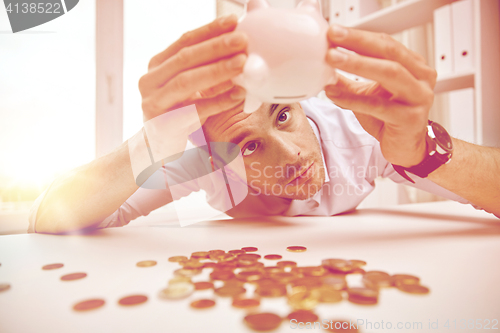 Image of businessman with piggy bank and coins at office