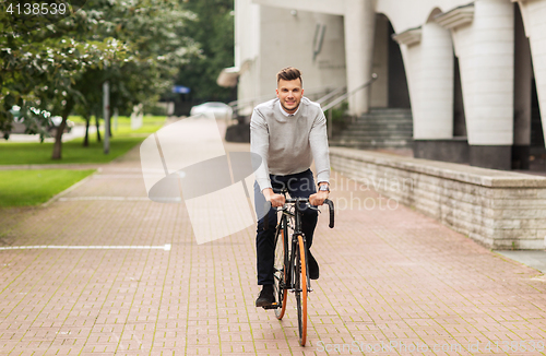 Image of young man riding bicycle on city street