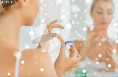 Image of young woman applying contact lenses at bathroom