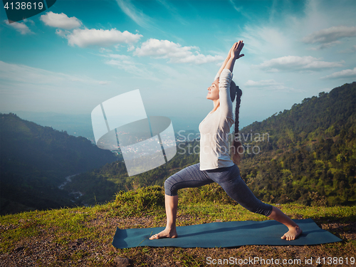 Image of Woman doing yoga asana Virabhadrasana 1 - Warrior pose outdoors