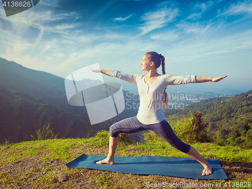 Image of Woman doing yoga asana Virabhadrasana 2 - Warrior pose outdoors