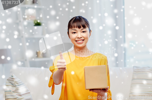 Image of happy asian young woman with parcel box at home