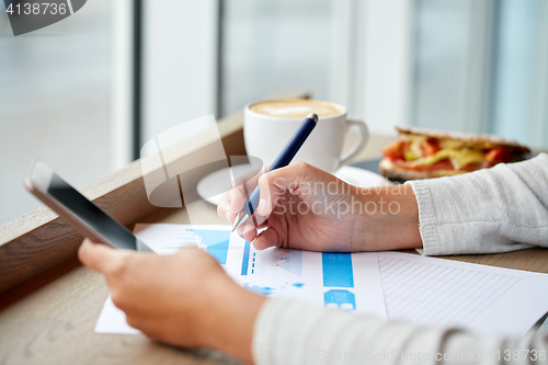 Image of woman with smartphone and chart at cafe