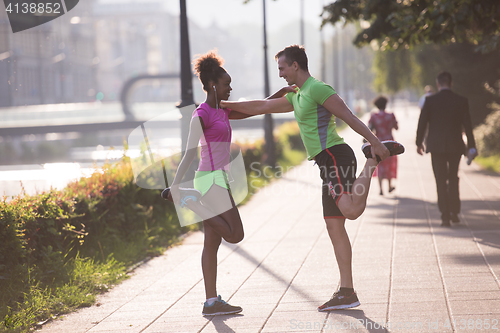 Image of jogging couple warming up and stretching in the city