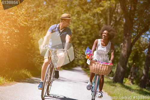 Image of Young multiethnic couple having a bike ride in nature