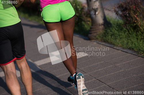 Image of young smiling multiethnic couple jogging in the city