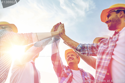 Image of close up of builders in hardhats making high five