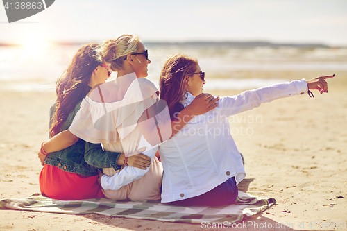 Image of group of smiling women in sunglasses on beach