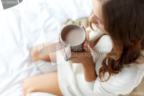 Image of close up of woman with cocoa cup in bed at home