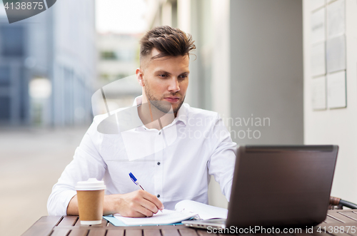 Image of man with laptop and coffee at city cafe