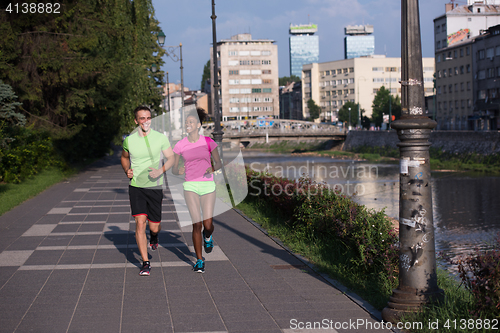 Image of young smiling multiethnic couple jogging in the city