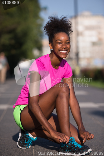 Image of African american woman runner tightening shoe lace