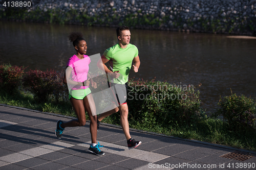 Image of young smiling multiethnic couple jogging in the city