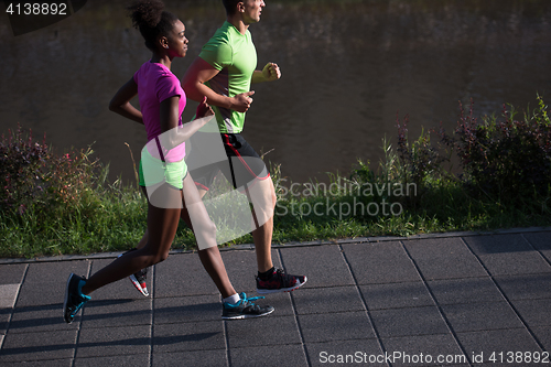 Image of young smiling multiethnic couple jogging in the city