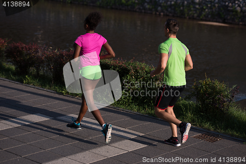Image of young smiling multiethnic couple jogging in the city