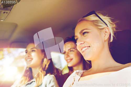 Image of happy teenage girls or young women driving in car