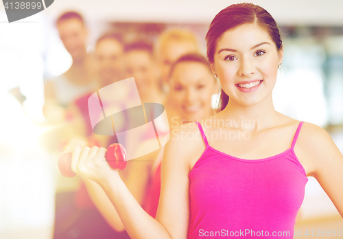 Image of group of smiling people with dumbbells in the gym