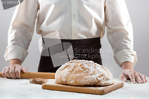 Image of The male hands and rustic organic loaf of bread