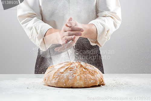 Image of The male hands in flour and rustic organic loaf of bread