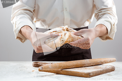 Image of Baker man holding rustic organic loaf of bread in hands