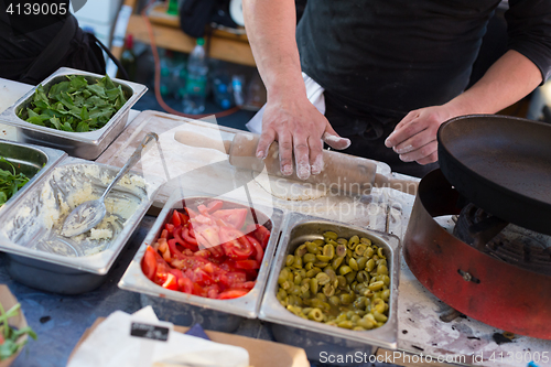 Image of Chef making pita bread for falafel roll outdoor on street stall.
