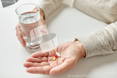 Image of close up of old man hands with pills and water