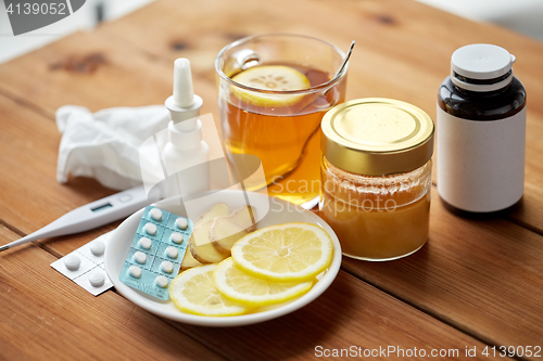 Image of drugs, thermometer, honey and cup of tea on wood