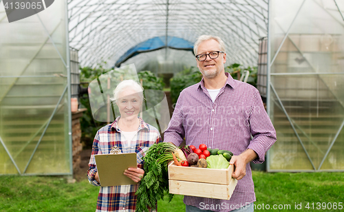 Image of senior couple with box of vegetables on farm